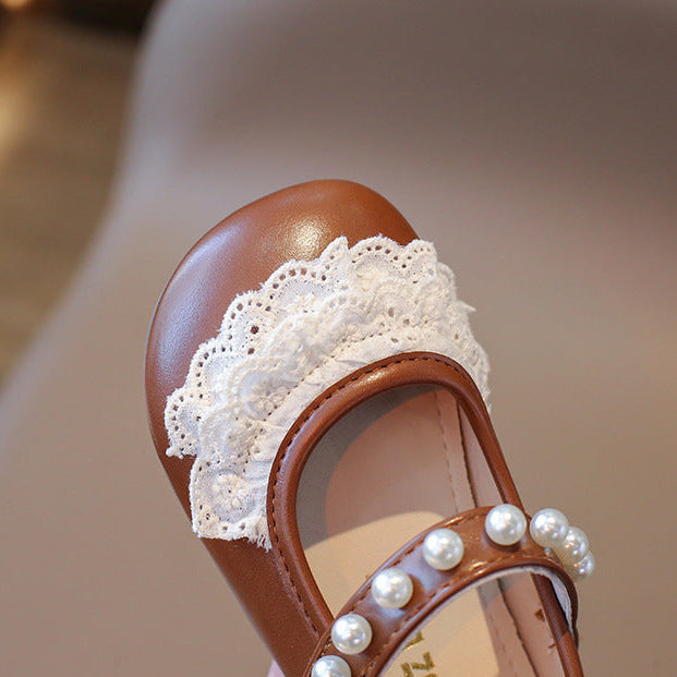 Brown sandal with white lace and pearls on a blurred background