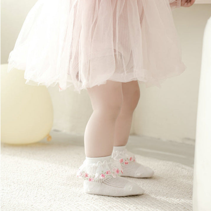 Child wearing white socks with pink designs on a light background