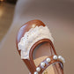 Brown sandal with white lace and pearls on a blurred background