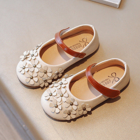 Pair of white children's shoes with floral designs on a light surface