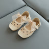 Beige children's shoes with heart patterns and ribbons on a gray surface