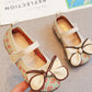 Children's shoes with floral pattern and bow detail on a neutral background