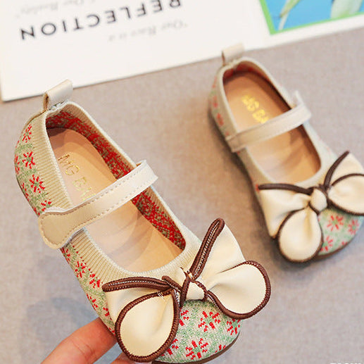 Children's shoes with floral pattern and bow detail on a neutral background