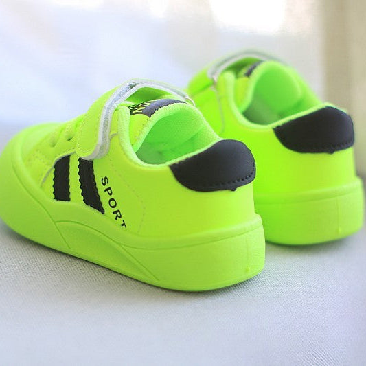 Neon green sports shoes with black accents on a light gray surface.