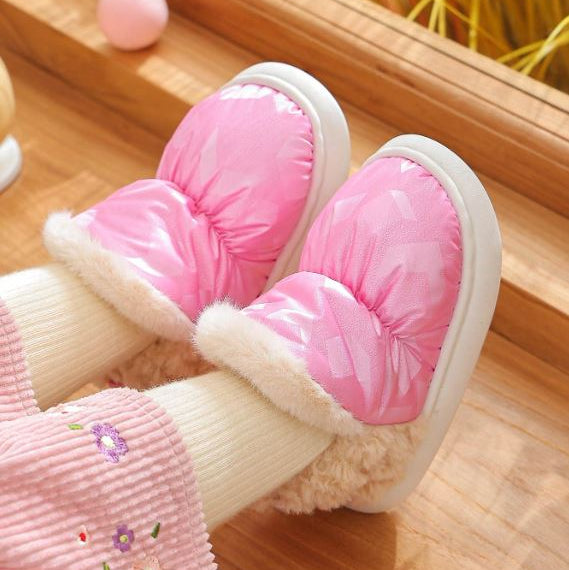 Pink and white baby shoes with fluffy texture on a wooden floor.