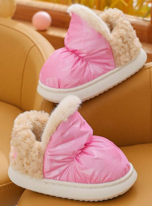 Pink and beige slippers with fluffy texture on a brown chair.