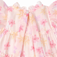 Close-up of a floral dress with pink and yellow flowers on a light background