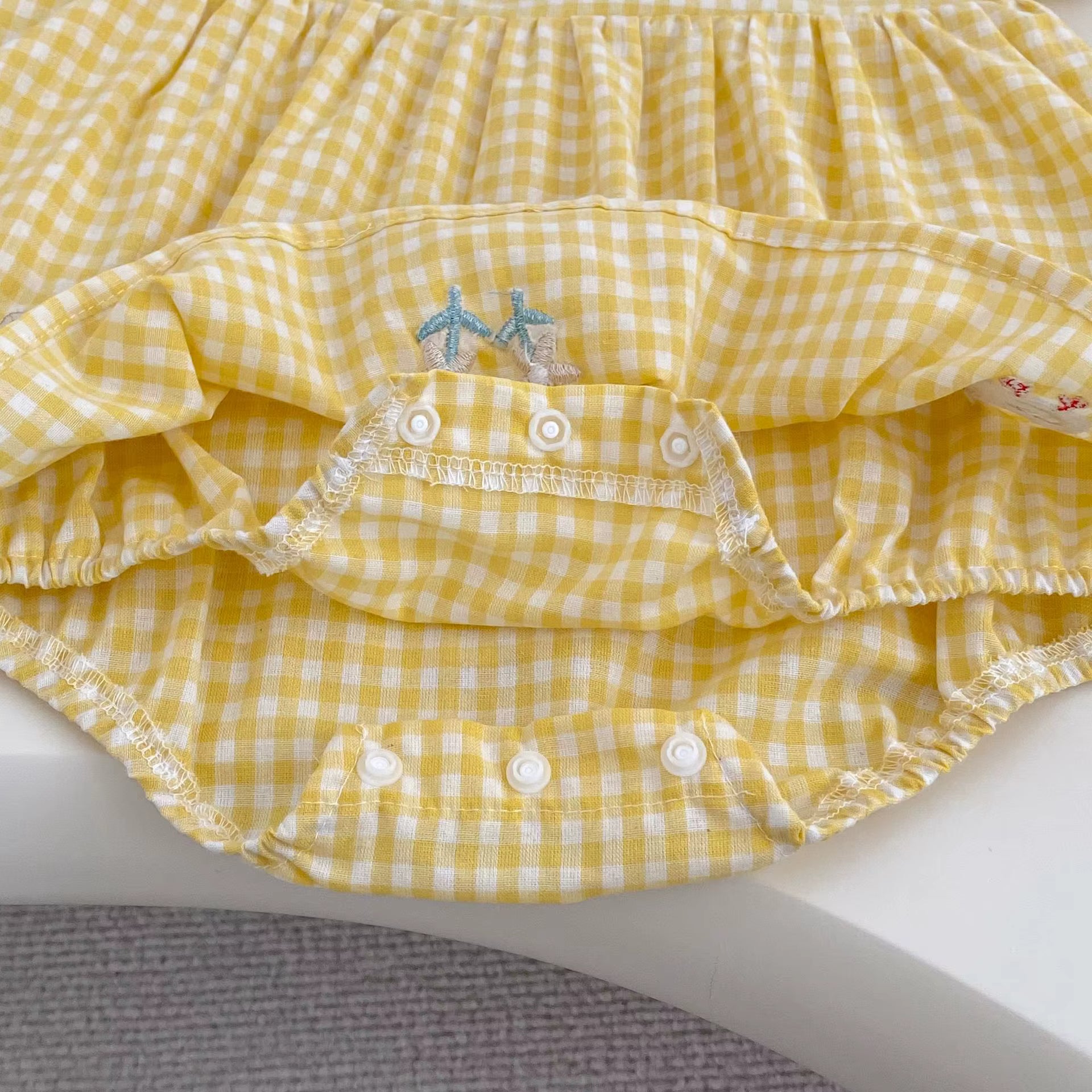 Yellow gingham baby romper with buttons closure