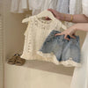 Baby outfit with lace top and denim shorts on a hanger, with a hand holding the shorts.