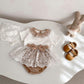 Baby outfit set with lace top, skirt, and shoes on a white surface.