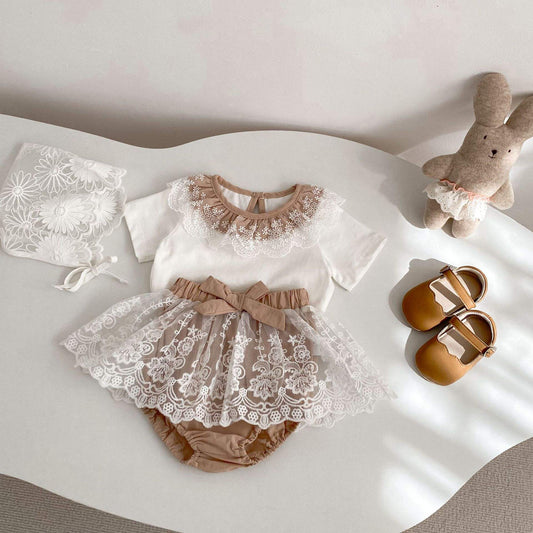 Baby outfit set with lace top, skirt, and shoes on a white surface.