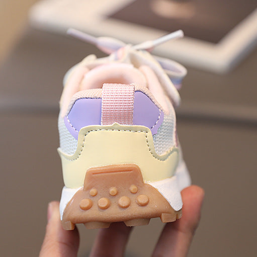 Colorful sneaker with a unique sole design held by a hand against a blurred background