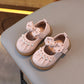 Pair of pink children's shoes with decorative bows on a light surface.