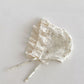 Floral lace baby bonnet on a light gray background