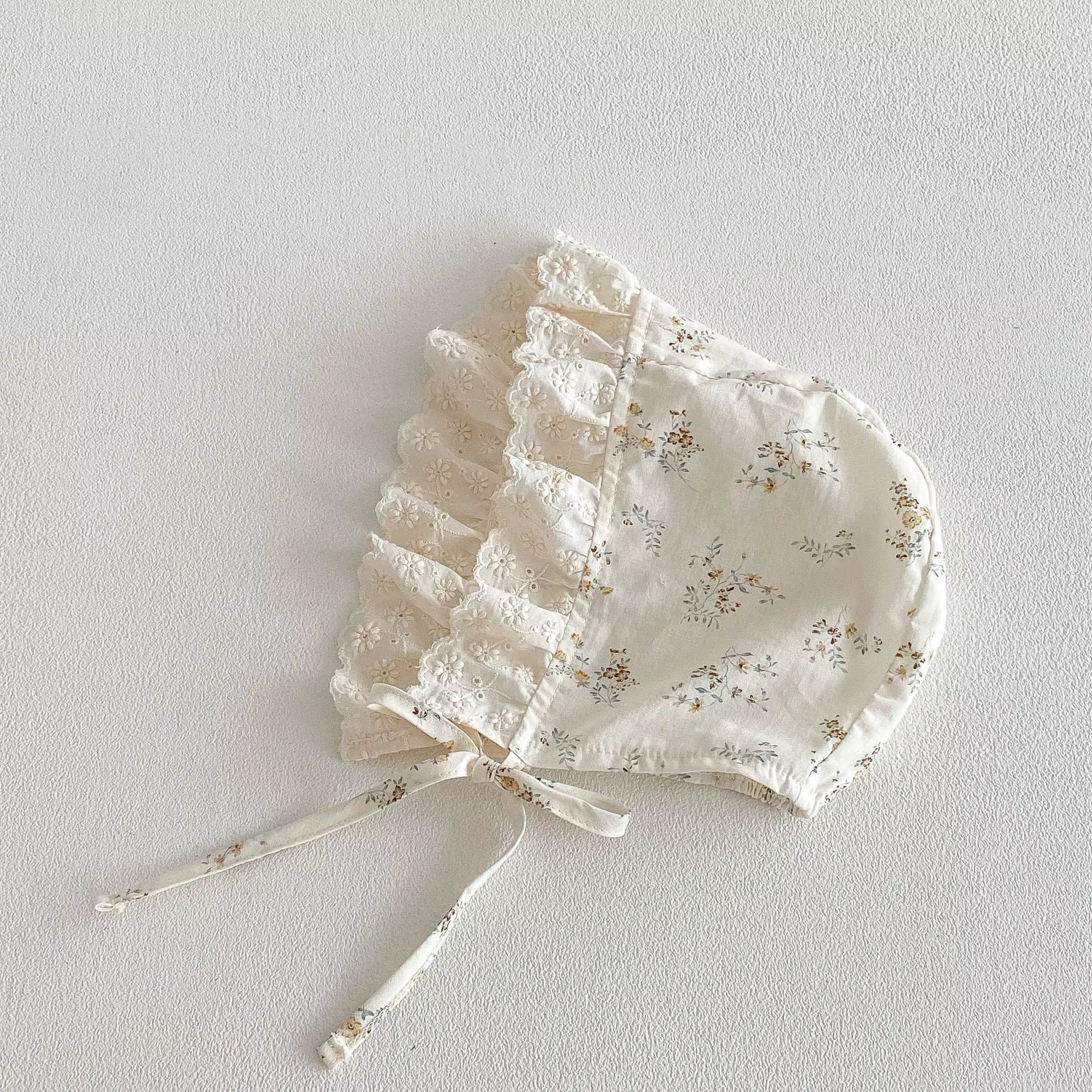 Floral lace baby bonnet on a light gray background