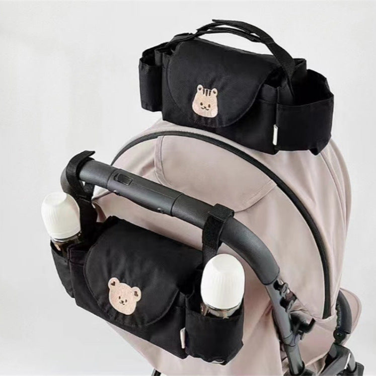Black baby stroller organizer with bear designs attached to a stroller 