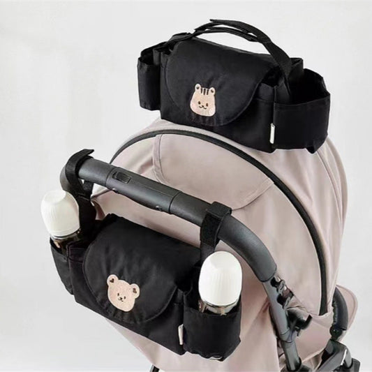 Black baby stroller organizer with bear designs attached to a stroller 