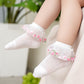 White socks with floral decorations worn by a child, with a blurred background.
