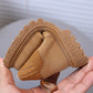 Folded brown fabric with textured edges held in a hand against a neutral background
