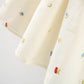 White fabric with colorful embroidered designs on a light gray background
