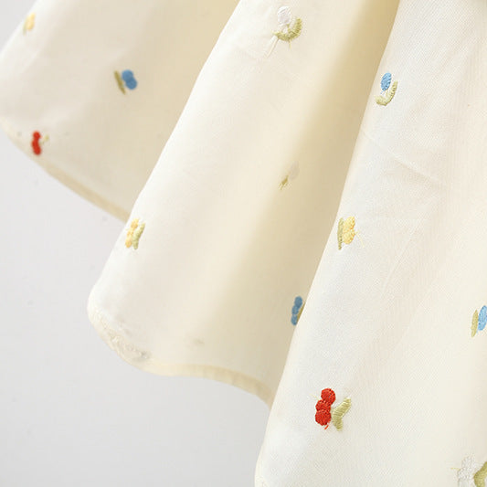 White fabric with colorful embroidered designs on a light gray background