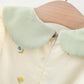 Light green collar on a garment with a wooden surface in the background