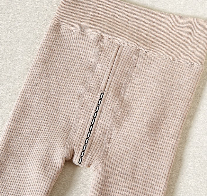 Close-up of beige ribbed leggings with a plain background