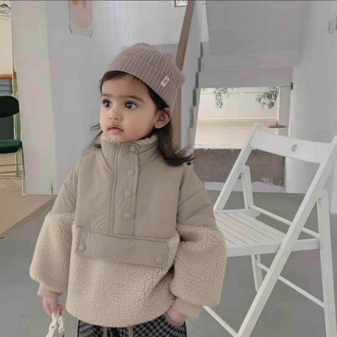 Child wearing a beige coat and knit hat indoors