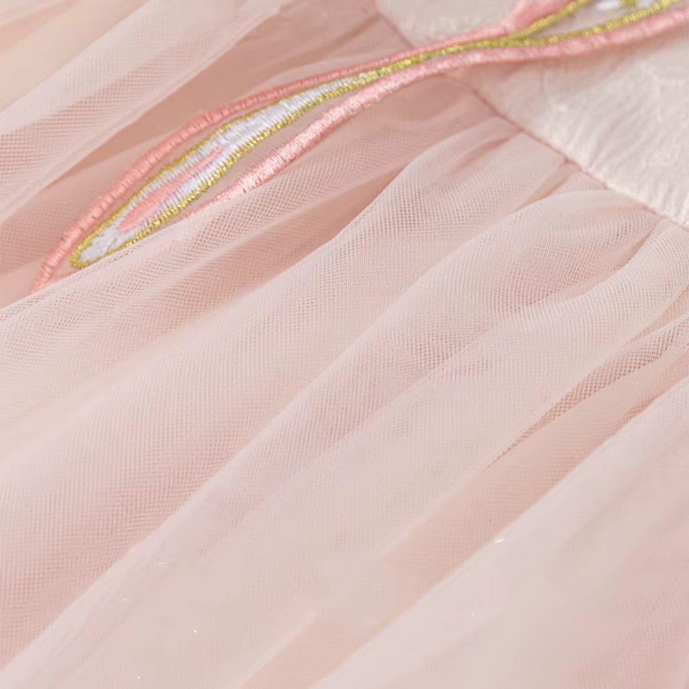 Close-up of a pink dress with gold embroidery on a light pink background