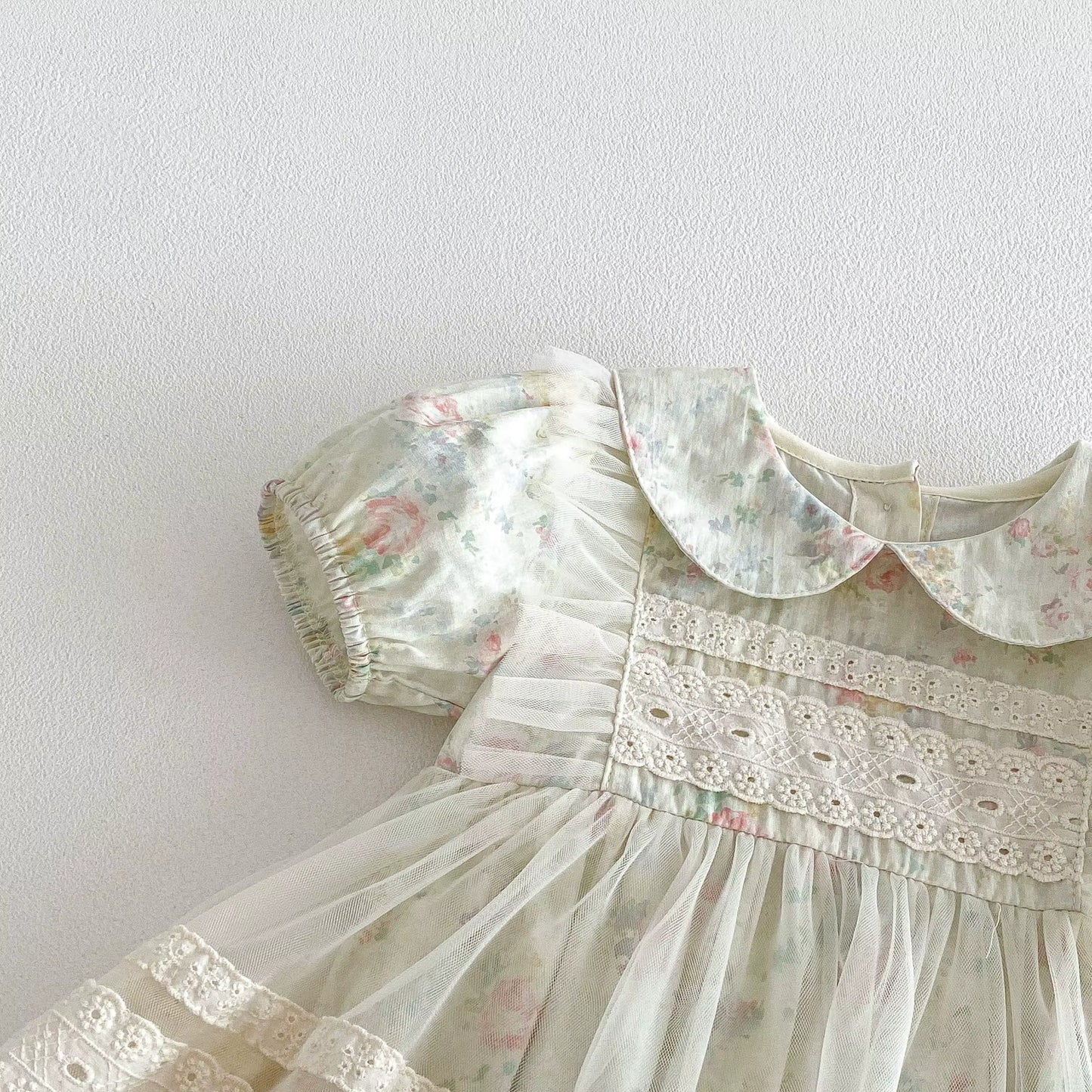 Vintage-style dress with floral patterns and lace details on a plain background