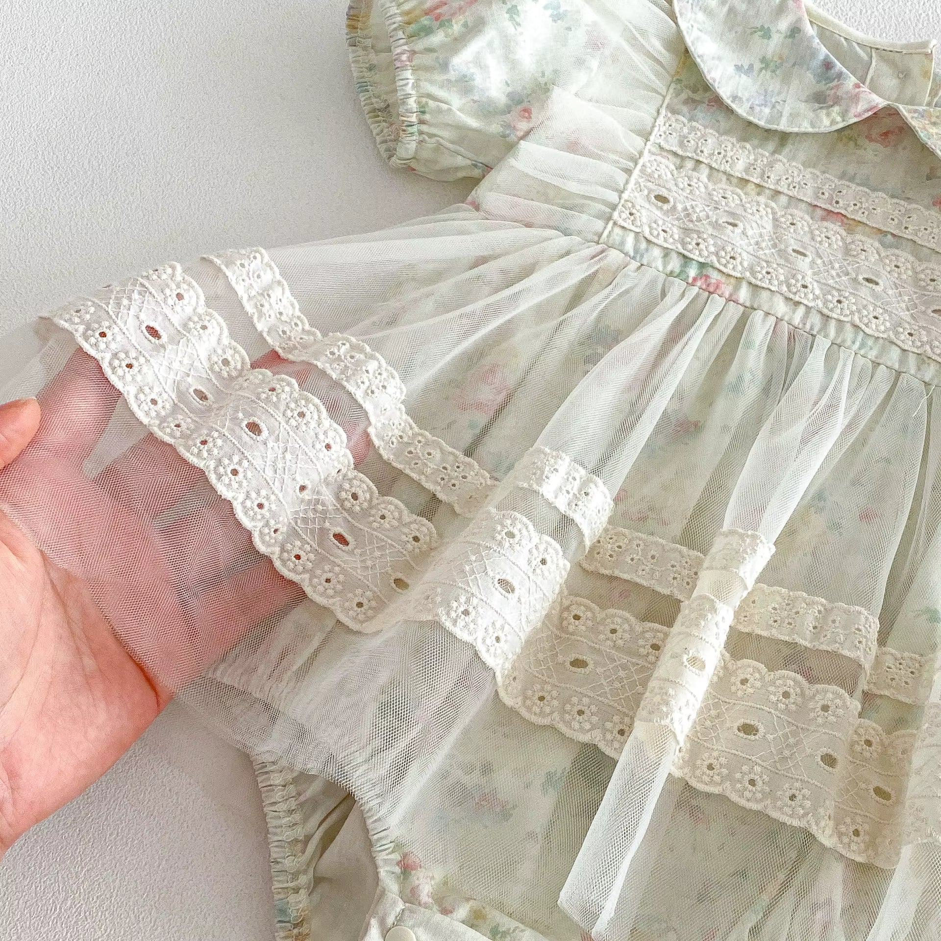 Close-up of a delicate lace-trimmed dress with floral patterns for baby girls