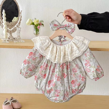 Floral baby romper with lace collar on a hanger against a neutral background